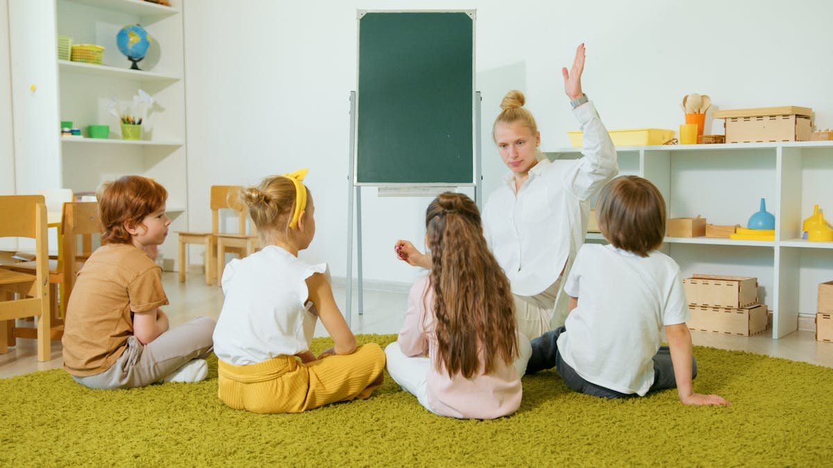 Educator seated at children's level on the carpet, listening and engaging
