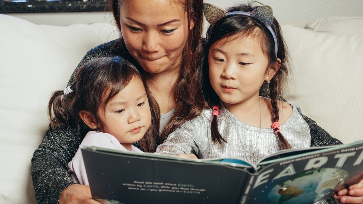 A parent reading a book with her young children
