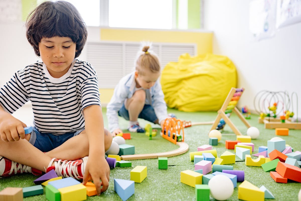 Two preschoolers playing with wooden blocks in self-directed play